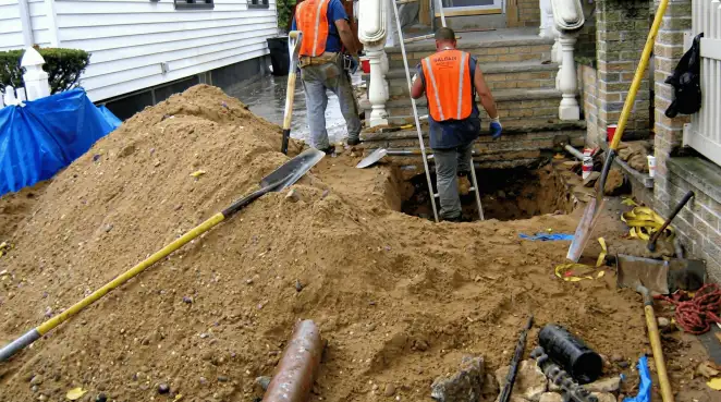 Contractors performing foundation protection and exterior drainage excavation near residential home steps in Raleigh, NC