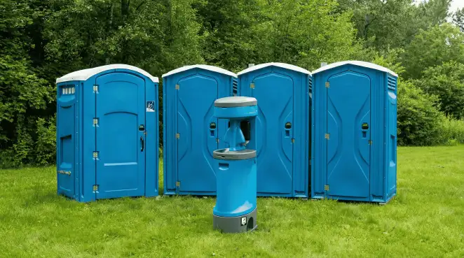 Four blue portable toilets and a matching hand washing station on grass near trees, a common sight at local outdoor events in Raleigh, NC